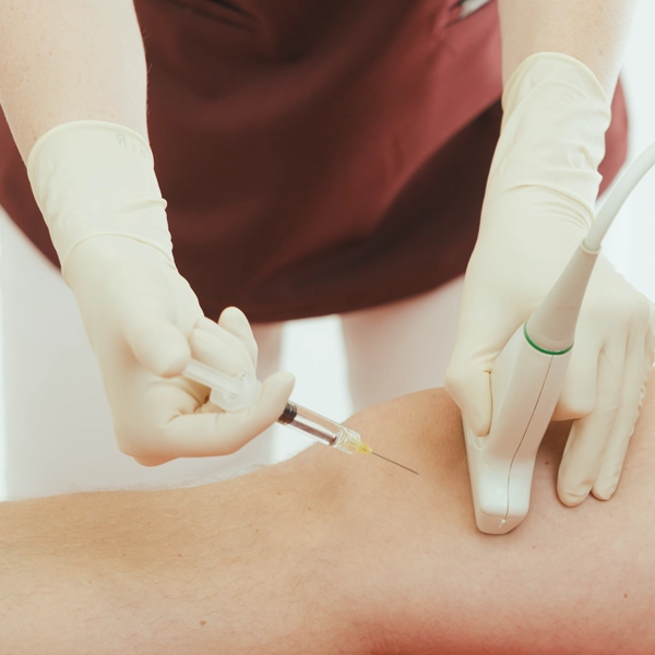 Frau Dr. Limbrock, Fachärztin für Orthopädie, appliziert eine präzise Injektion am Kniegelenk unter Ultraschallkontrolle im Rahmen einer schmerztherapeutischen Behandlung.