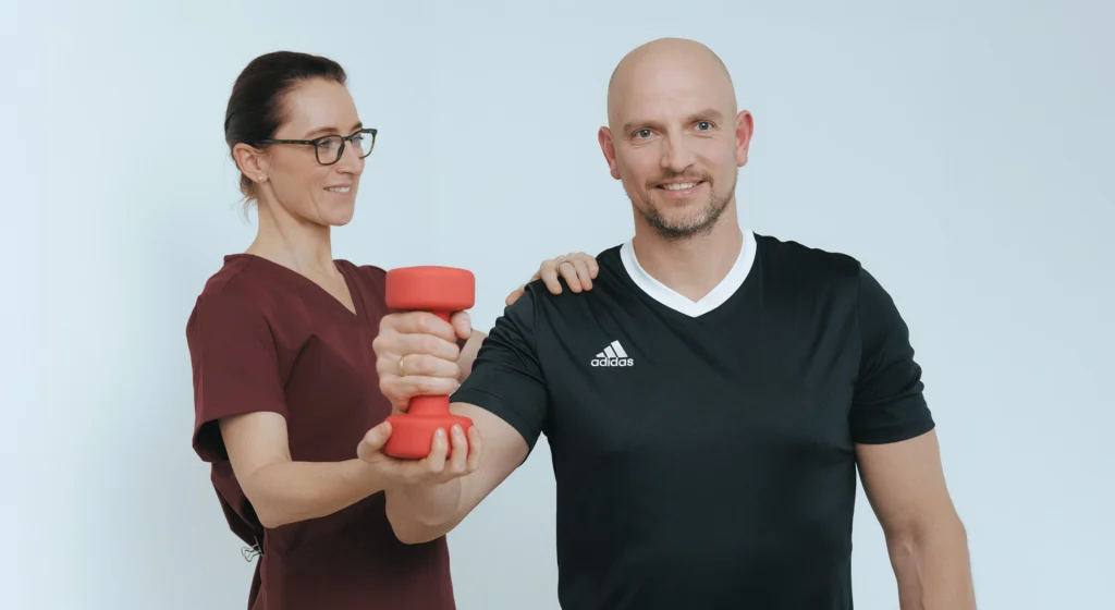 Orthopädin Frau Dr. Limbrock unterstützt einen Patienten beim Training der Armmuskulatur.