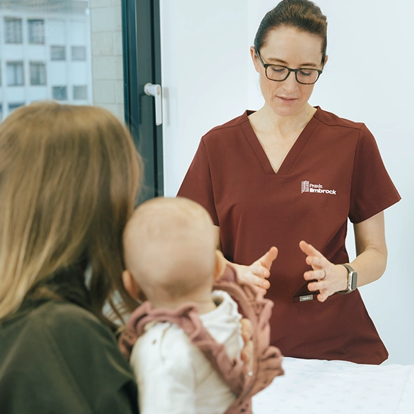 Frau Dr. Limbrock erklärt einer Mutter mit ihrem Baby eine kinderorthopädische Untersuchung in der Praxis.